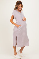 woman wearing a light purple maternity dress with pockets and side slits, gently cradling her baby bump