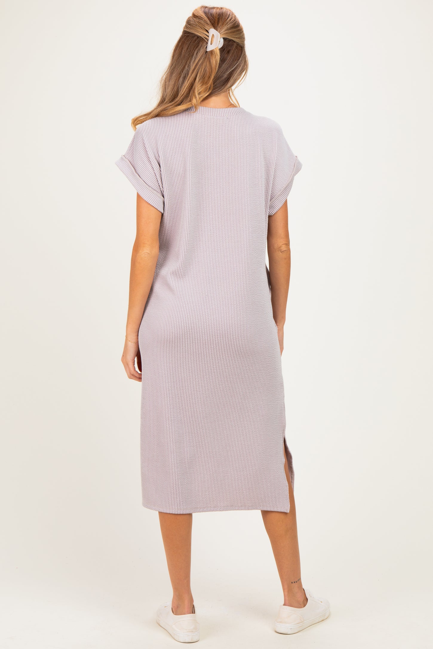 woman wearing a light purple maternity dress with short sleeves and side slits, showing a relaxed fit and casual style