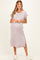 woman wearing a light purple striped maternity dress with rolled sleeves and side slits, showing her baby bump