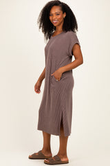 woman wearing a brown ribbed short sleeve midi dress with pockets and side slits, standing and smiling
