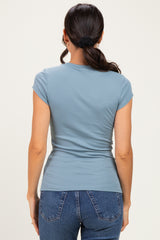 woman wearing a blue short sleeve fitted top and high-waisted jeans, viewed from the back