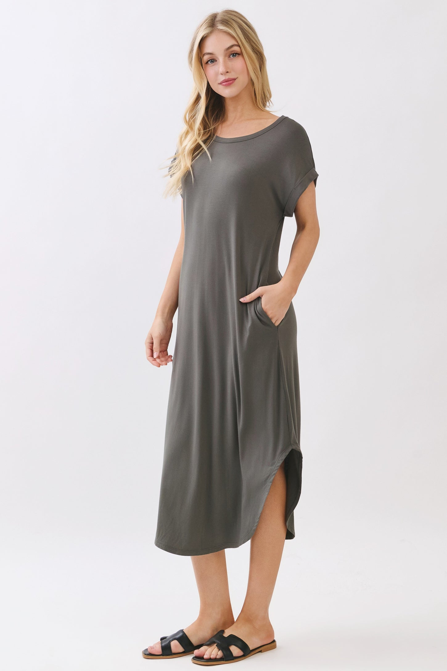 woman wearing a gray short sleeve midi dress with side pockets and a curved hemline