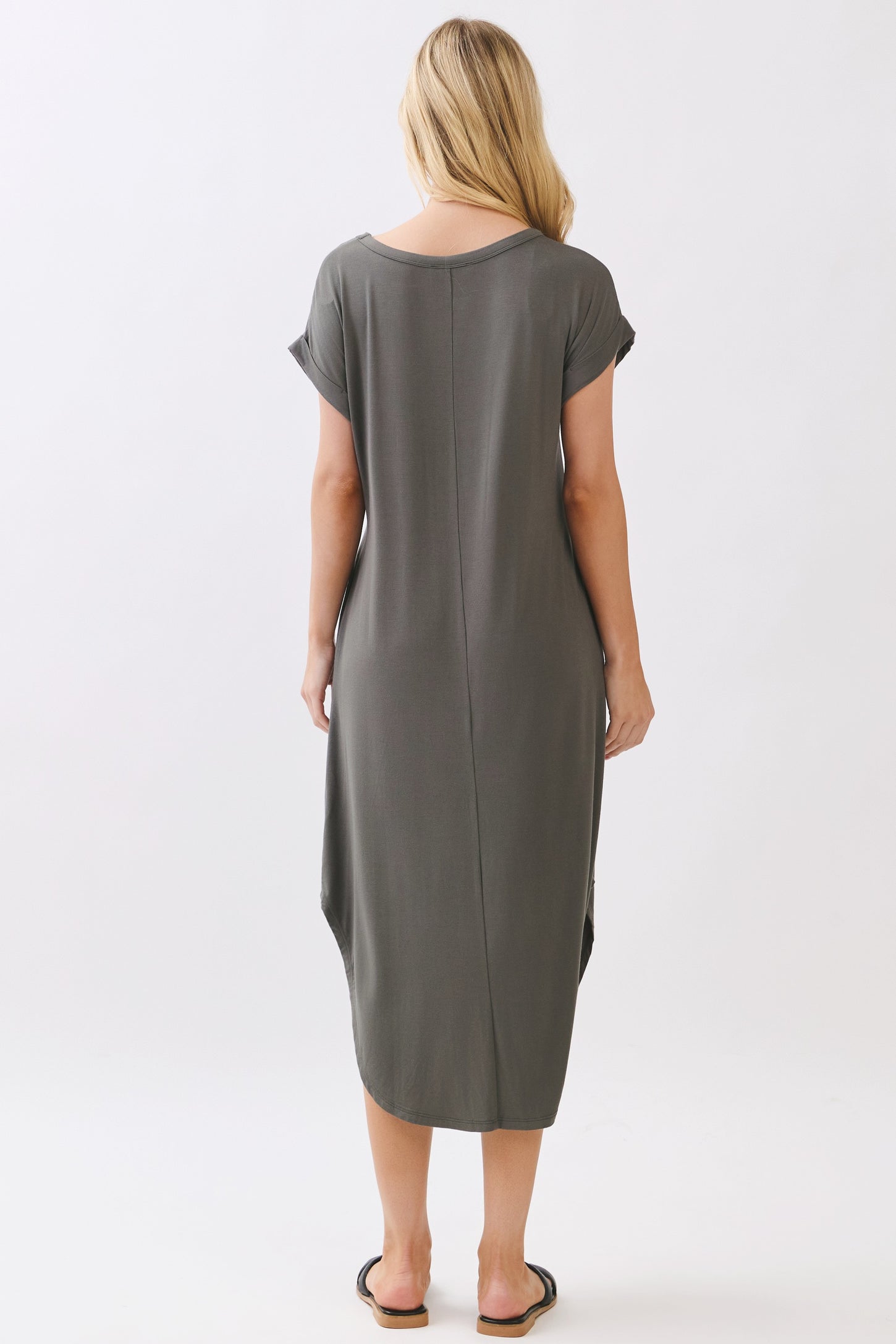 woman wearing a relaxed fit olive green maxi dress with short sleeves and side slits, viewed from the back