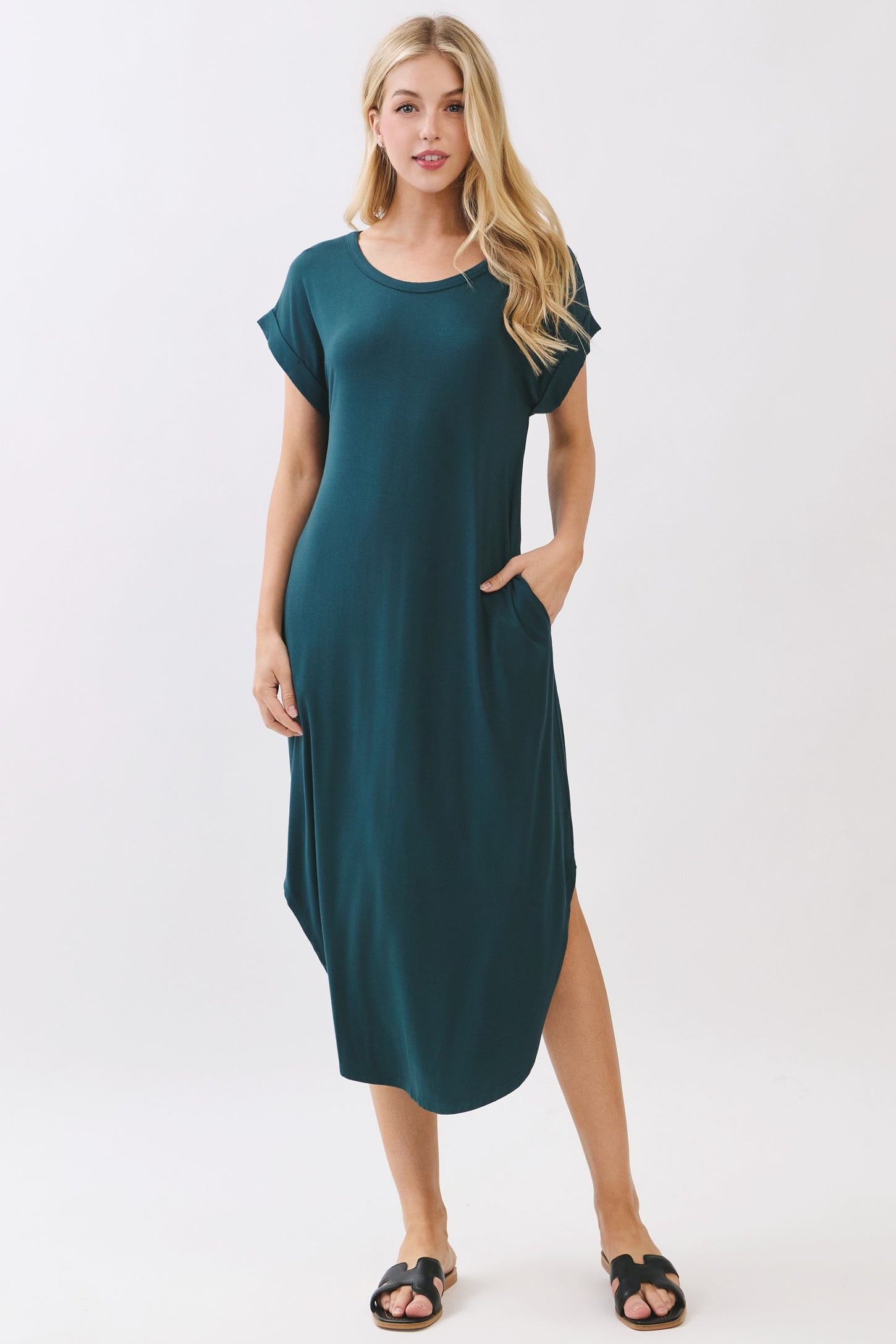 woman wearing a teal short sleeve maxi dress with pockets and side slits, styled with flat sandals