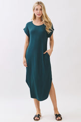 woman wearing a teal short sleeve maxi dress with pockets and side slits, styled with flat sandals