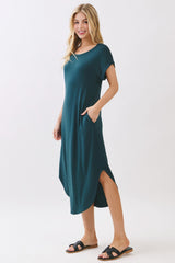 woman wearing a teal midi dress with short sleeves and side pockets, styled with black sandals