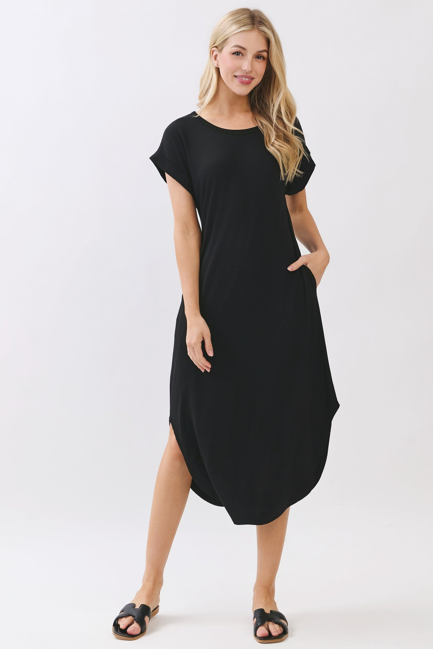 woman wearing a black short sleeve loose fit dress with pockets and side slits, styled with black sandals