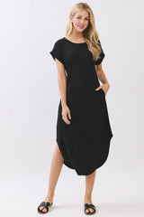 woman wearing a black short sleeve loose fit dress with pockets and side slits, styled with black sandals