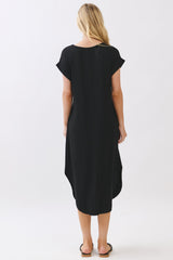 woman wearing a black short sleeve dress with a curved hem and relaxed fit, viewed from the back