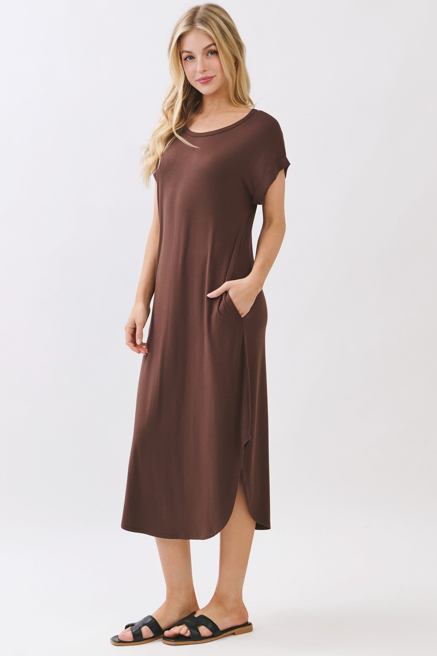 woman wearing a brown short sleeve maxi dress with side pockets and a side slit, standing in sandals