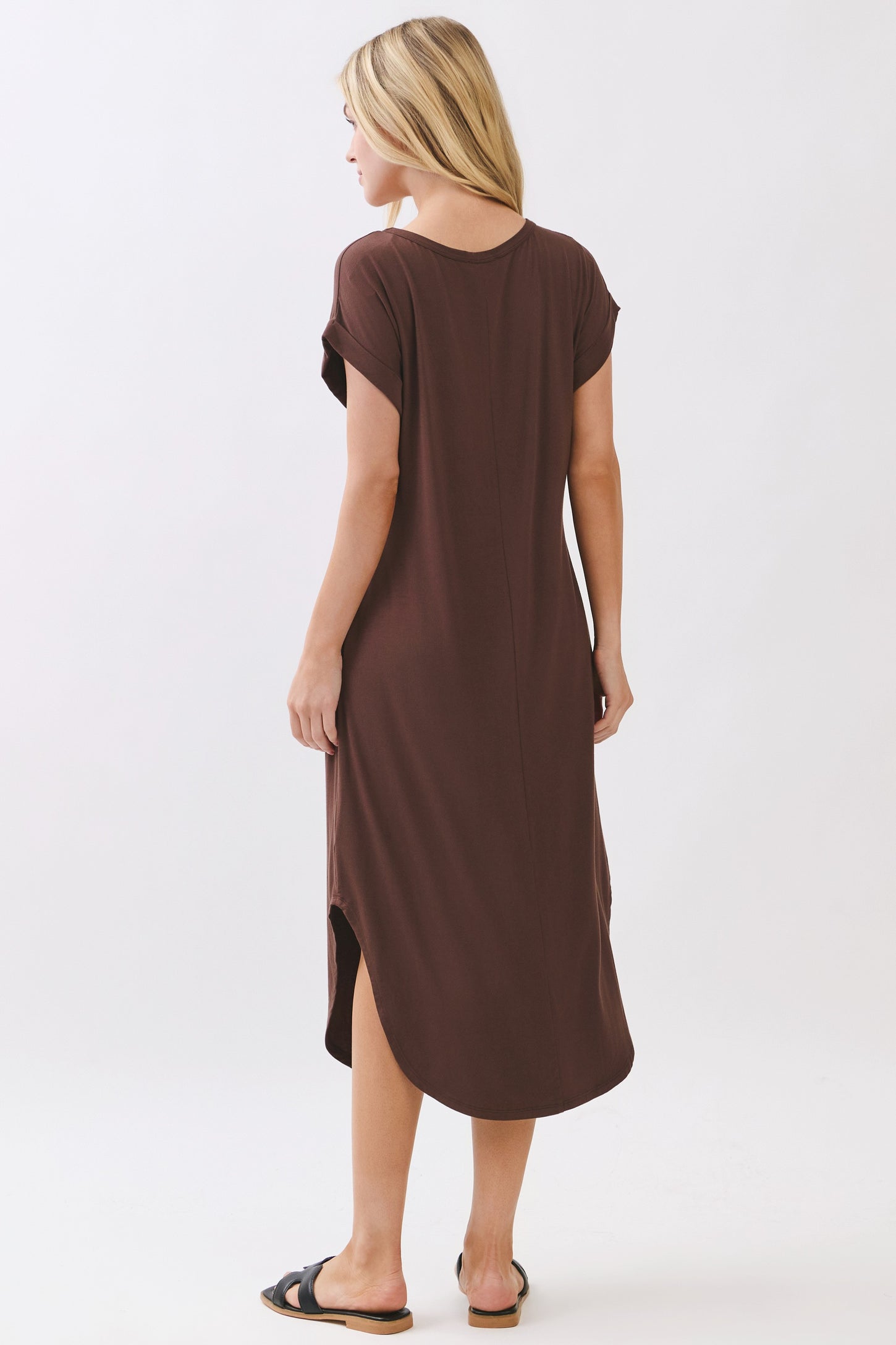 woman wearing a brown short sleeve maxi dress with a side slit and a relaxed fit, seen from the back