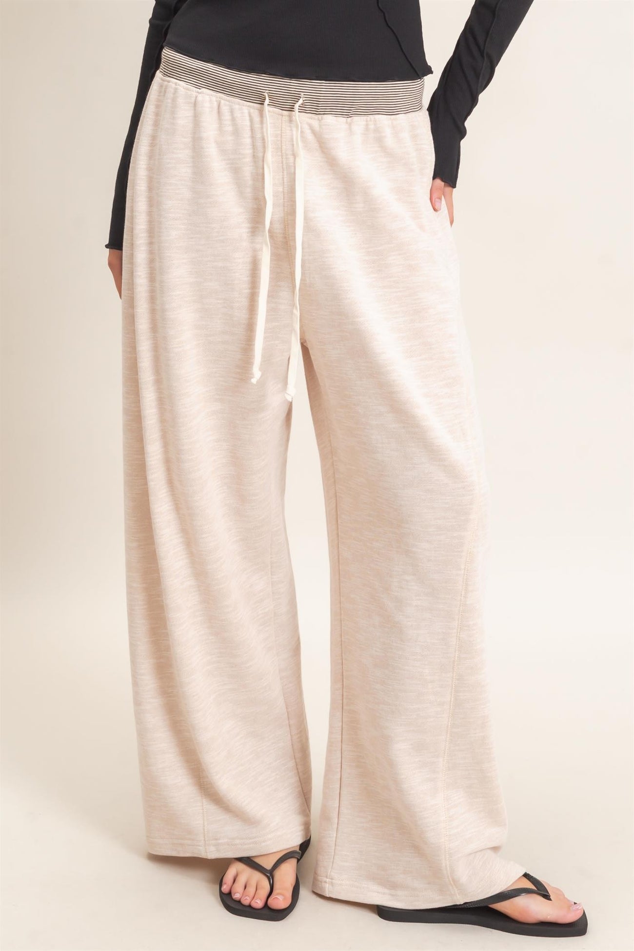 woman wearing cream wide-leg lounge pants with a drawstring waist and a grey waistband