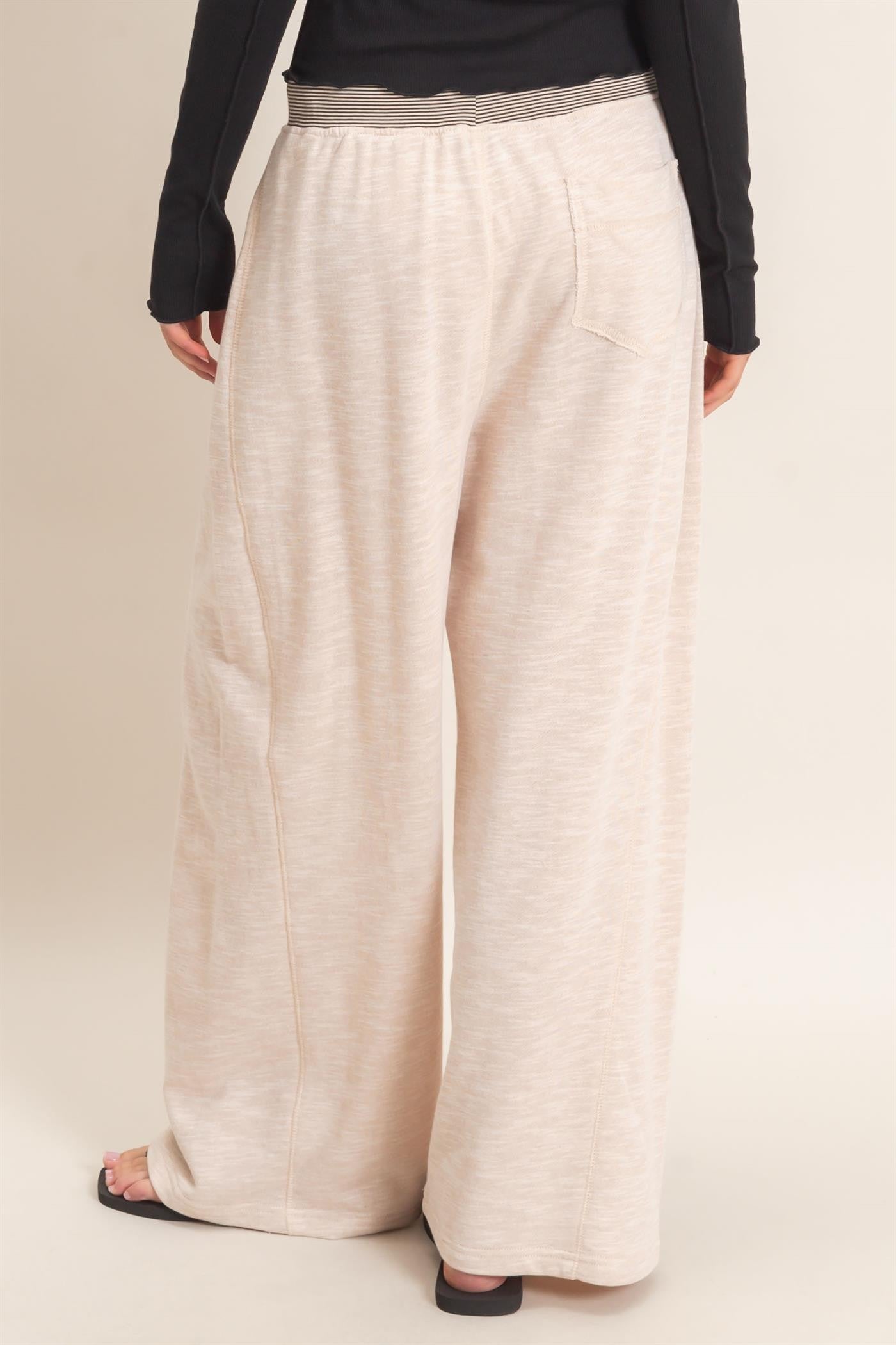 woman wearing light beige wide leg pants with an elastic waistband and a relaxed fit from the back