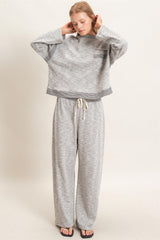 woman wearing a gray cropped sweatshirt with a pocket and matching wide-leg pants