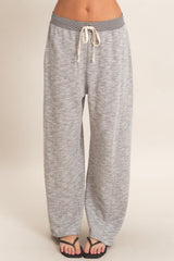 woman wearing gray lounge pants with a drawstring waistband and wide legs, standing against a neutral background