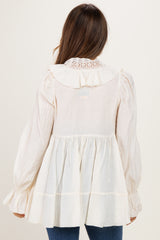 woman wearing a cream maternity top with a ruffled collar and long sleeves, showing a flowing silhouette from the back