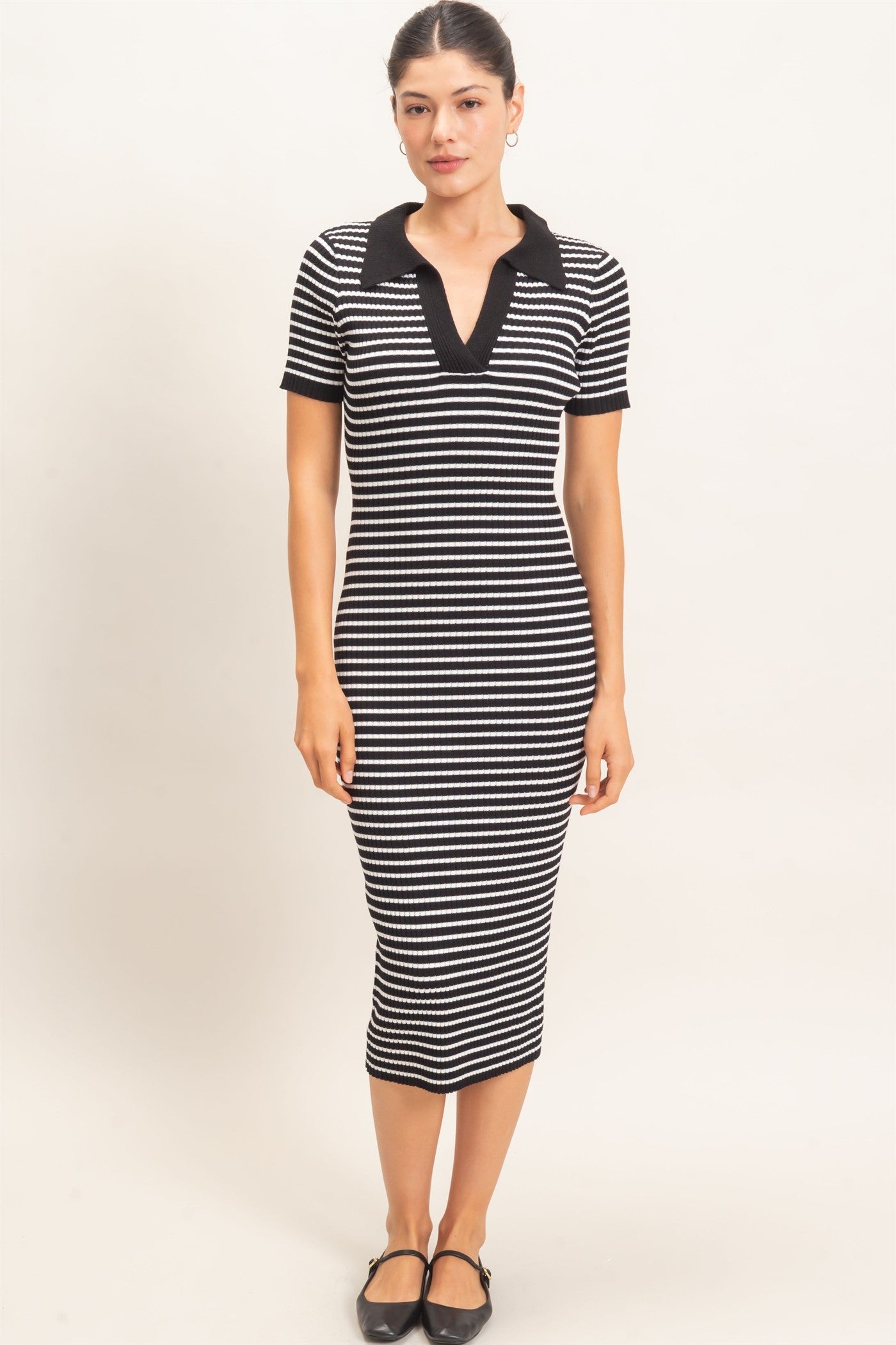 woman wearing a black and white striped midi dress with a polo collar and short sleeves