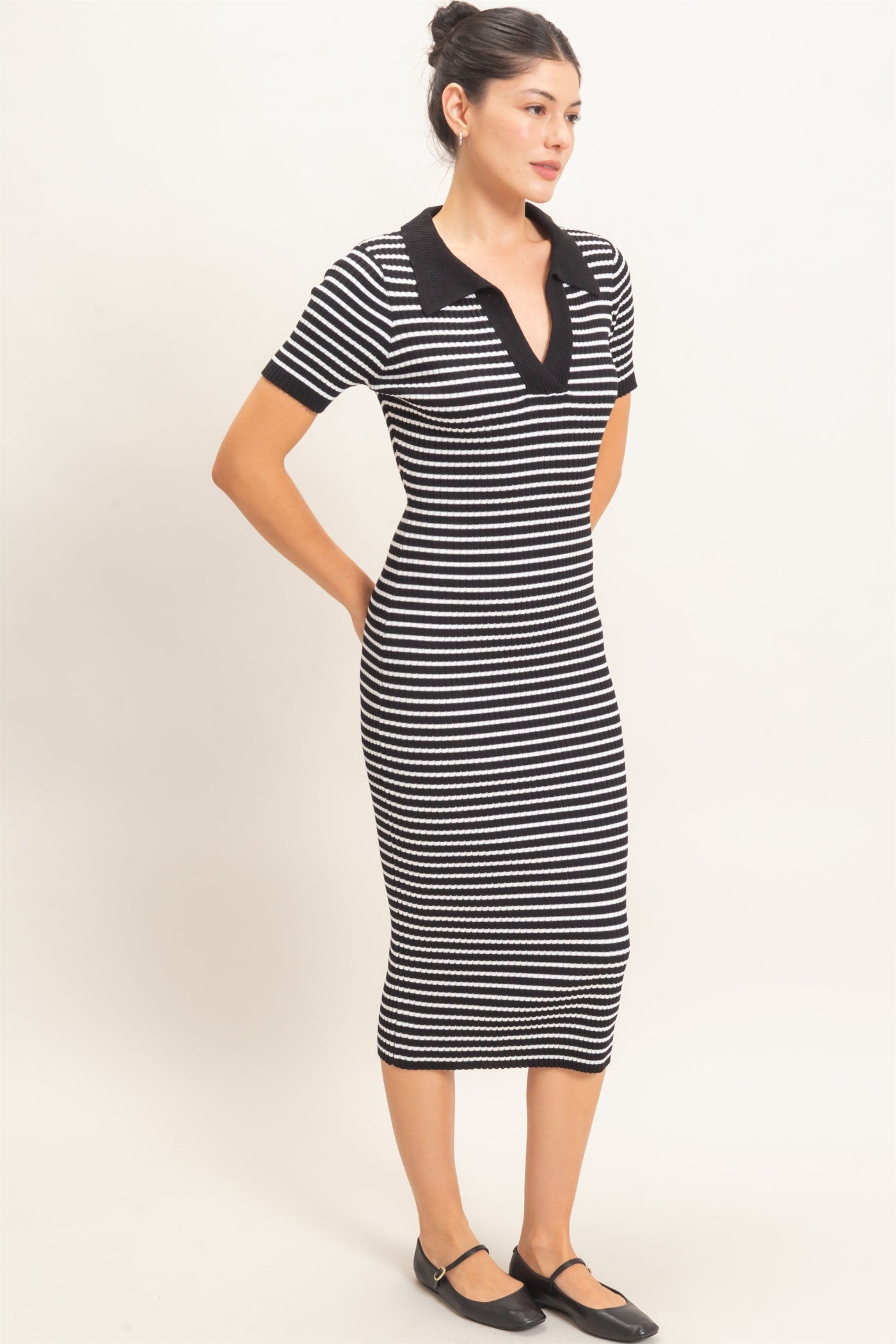 woman wearing a black and white striped short sleeve midi dress with a v-neck and black collar