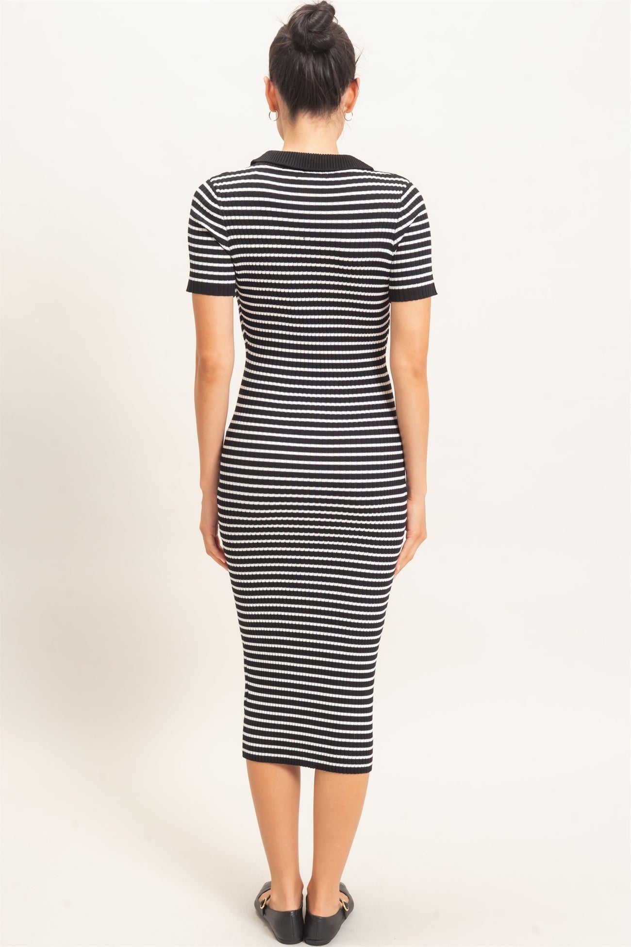 woman wearing a black and white striped midi dress with a fitted silhouette and short sleeves, seen from the back