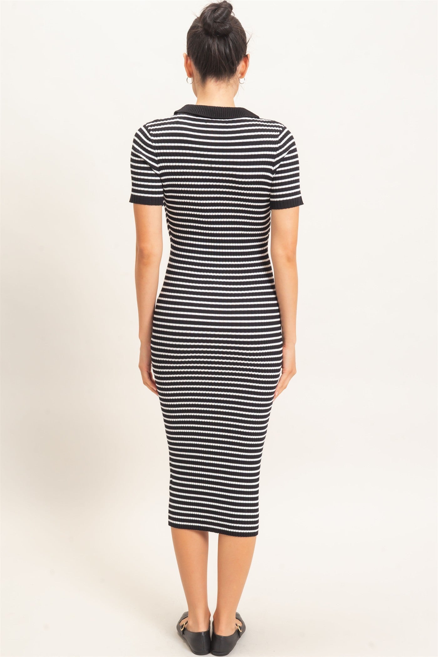woman wearing a black and white striped midi dress with a fitted silhouette and short sleeves, seen from the back