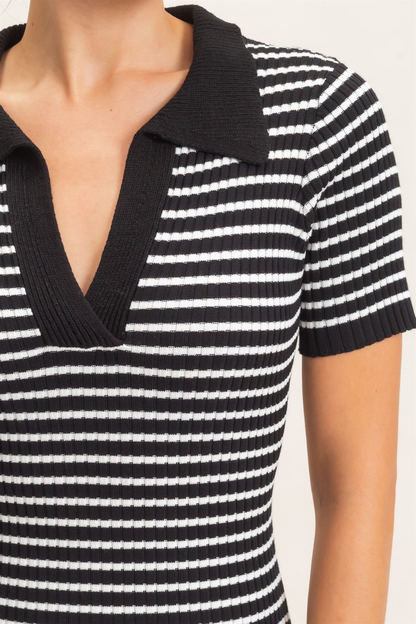 woman wearing a black and white striped ribbed short sleeve dress with a v-neck and collar