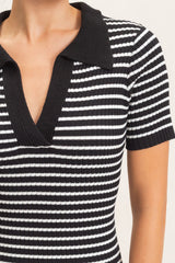 woman wearing a black and white striped ribbed short sleeve dress with a v-neck and collar
