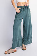 woman wearing green wide-leg lounge pants with a drawstring waist and side pockets, paired with tan sandals