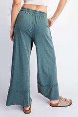 woman wearing loose-fitting teal wide-leg lounge pants with an elastic waistband and raw hem details