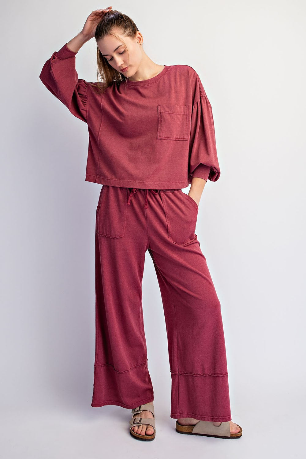woman wearing a rust-colored oversized sweatshirt with pocket and matching wide-leg pants