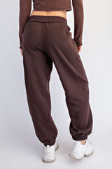 woman wearing brown sweatpants with elastic cuffs and a relaxed fit, showing the back view