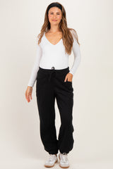 woman wearing a white long sleeve maternity bodysuit and black maternity jogger pants with pockets and drawstring waist