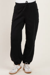 woman wearing black maternity jogger pants with elastic cuffs and pockets, styled with white sneakers