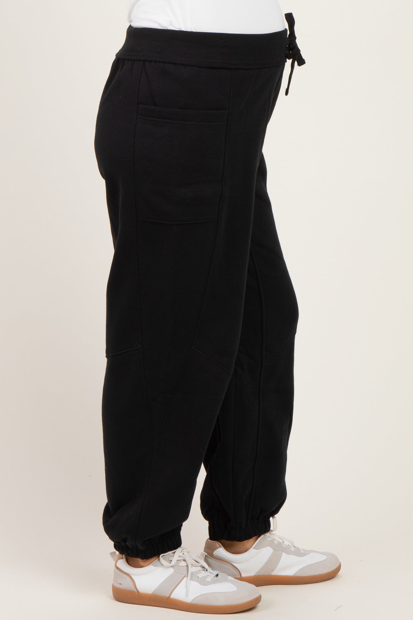 woman wearing black maternity joggers with side pockets and ankle cuffs, paired with white sneakers