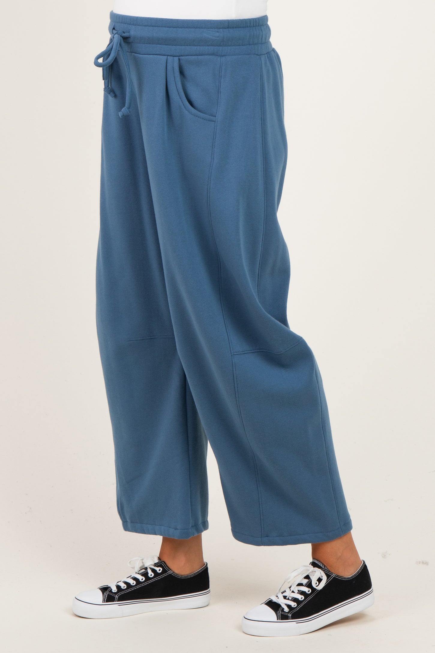 woman wearing blue maternity wide leg sweatpants with a drawstring waist and side pockets, paired with black sneakers