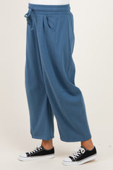 woman wearing blue maternity wide leg sweatpants with a drawstring waist and side pockets, paired with black sneakers
