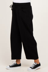 woman wearing black maternity jogger pants with an elastic waistband and side pockets, styled with black sneakers