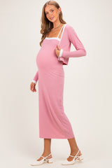 woman wearing a pink maternity dress with white straps and a long cardigan, showcasing her baby bump