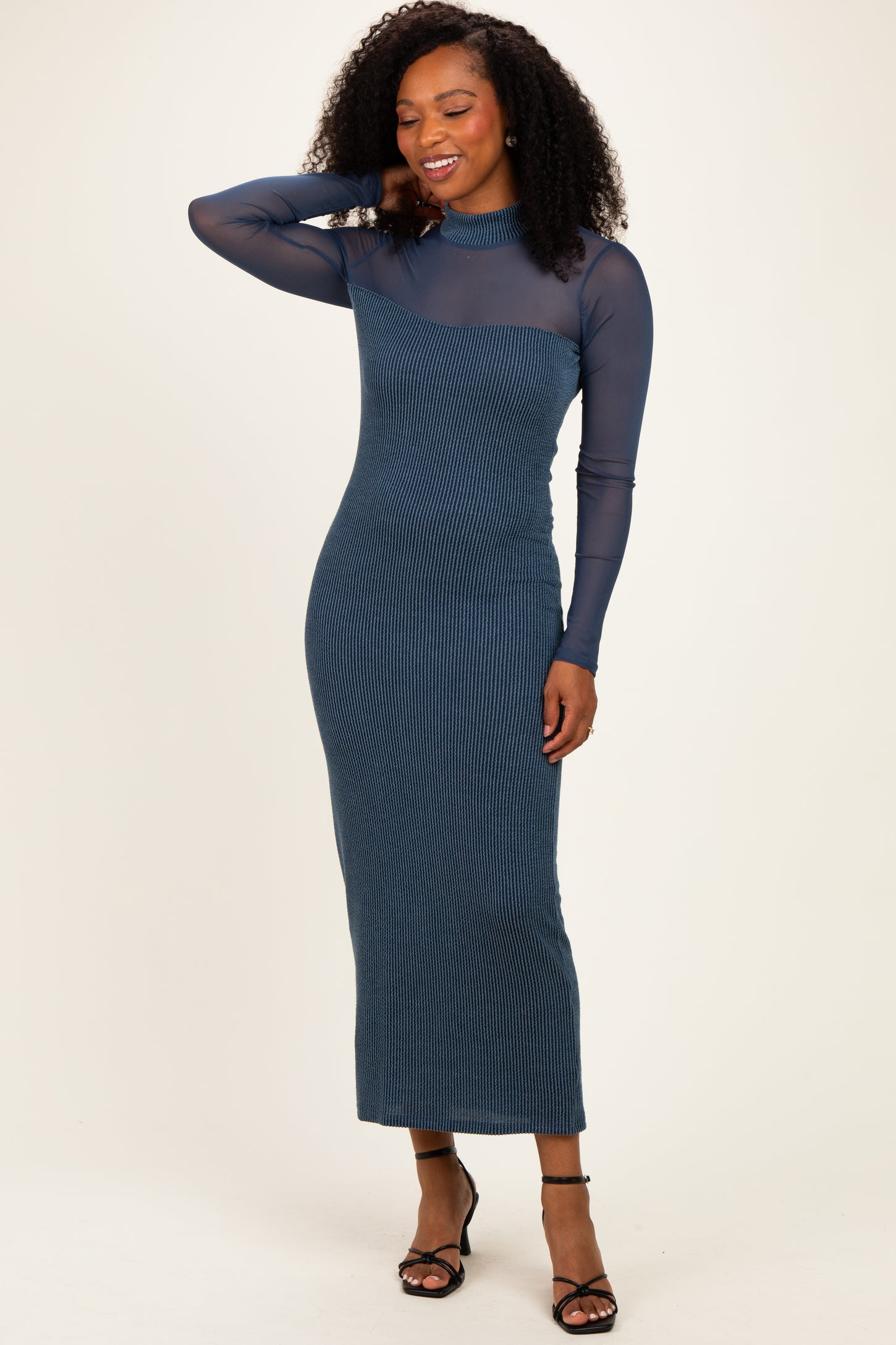 woman wearing a long sleeve dark blue ribbed midi dress with a sheer top and a fitted silhouette