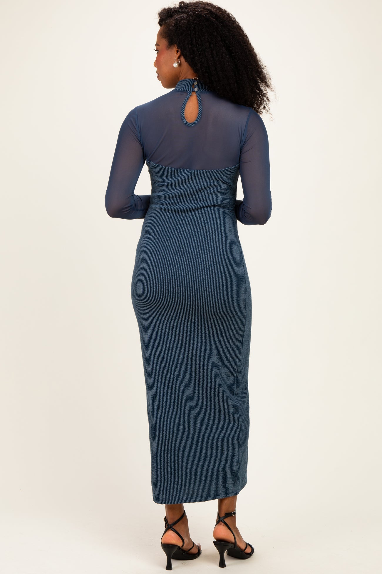 woman wearing a long sleeve blue ribbed maxi dress with a keyhole back and fitted silhouette