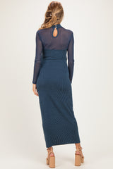 woman wearing a navy blue maternity dress with long sleeves and a back keyhole detail, showcasing a baby bump