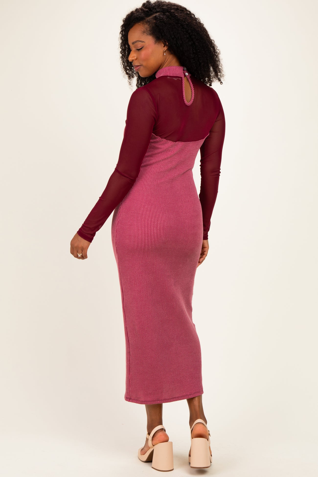 woman wearing a burgundy ribbed long sleeve maxi dress with a sheer back and a high neckline