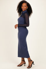 woman wearing a navy blue ribbed knit long sleeve dress with a sheer mesh top and fitted silhouette