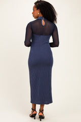 woman wearing a navy blue ribbed midi dress with long sheer sleeves and a keyhole back detail