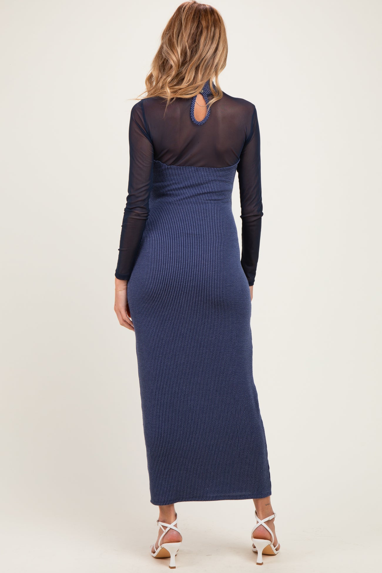 woman wearing a navy blue striped maternity maxi dress with a fitted silhouette and long sheer sleeves
