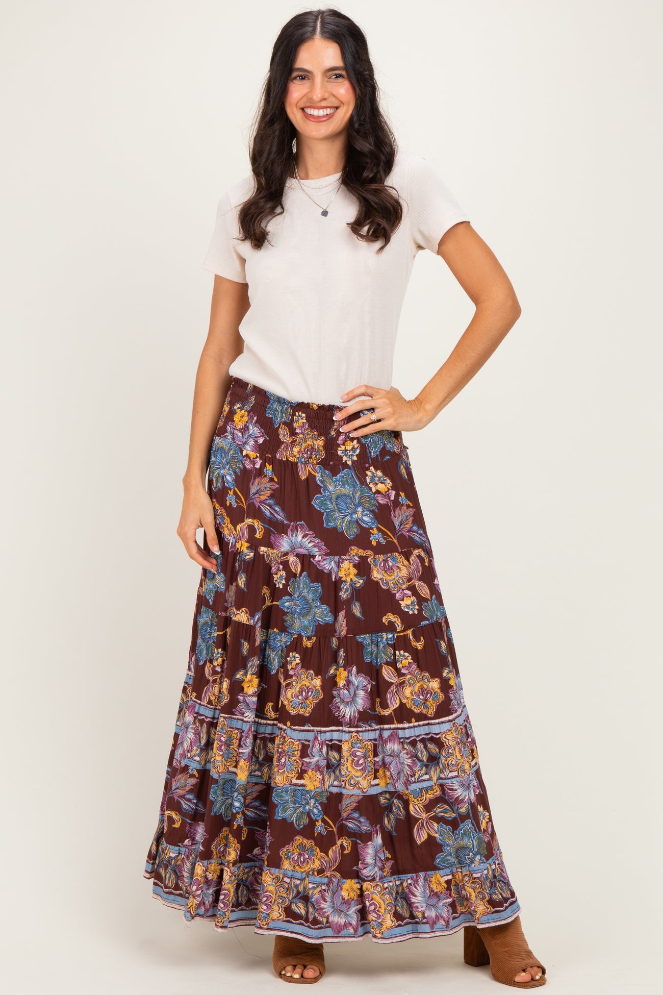 woman wearing a beige short sleeve top and a brown floral maxi skirt with a tiered design