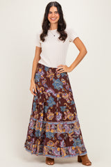 woman wearing a beige short sleeve top and a brown floral maxi skirt with a tiered design