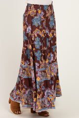 woman wearing a burgundy floral maxi skirt with a smocked waistband and layered ruffle hem