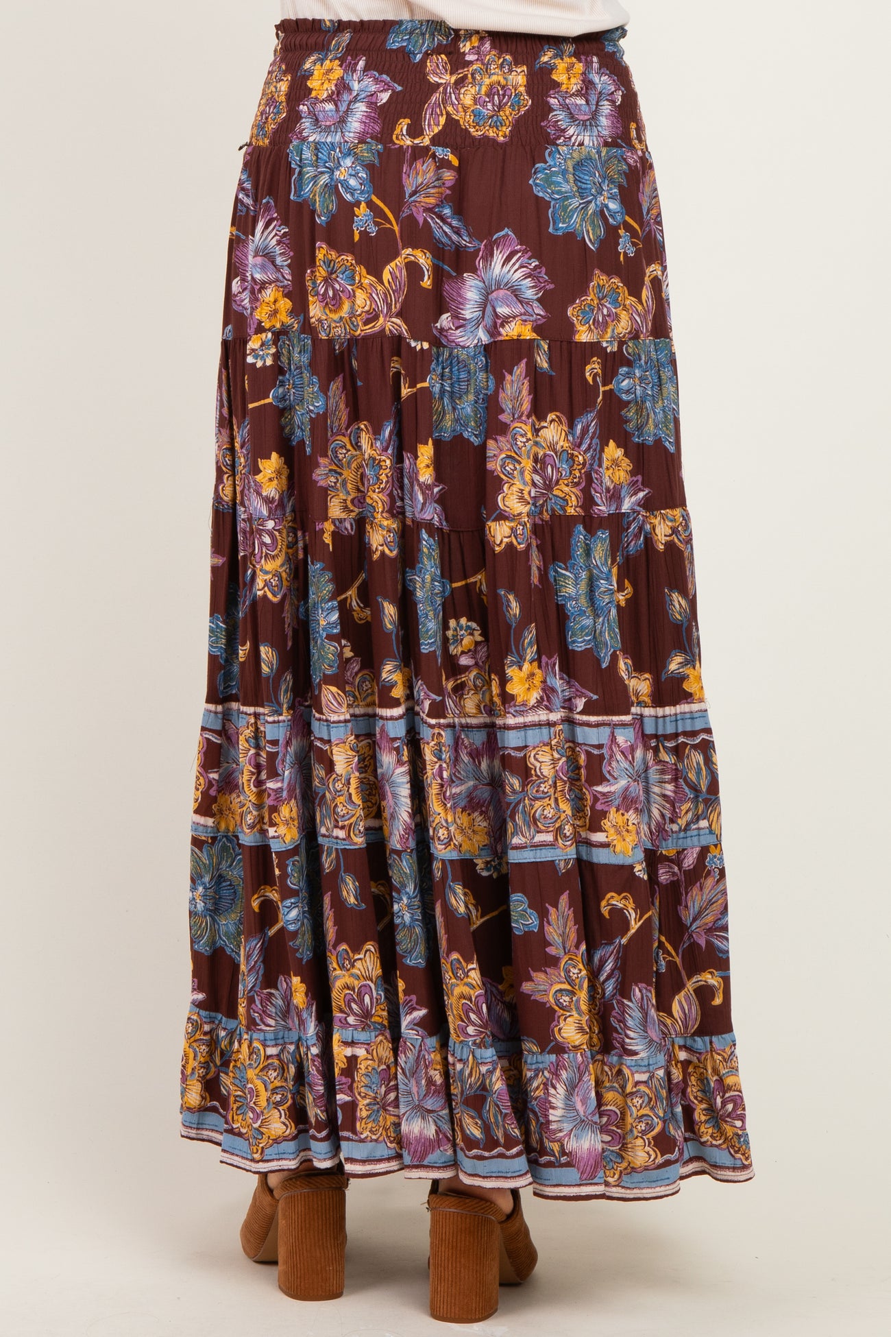 woman wearing a burgundy floral maxi skirt with layered ruffles and colorful floral patterns