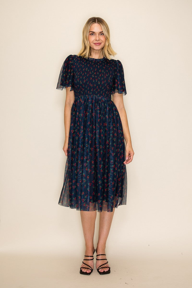 woman wearing a navy blue midi dress with floral print and puff sleeves, styled with black strappy sandals