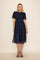 woman wearing a navy blue midi dress with floral print and puff sleeves, styled with black strappy sandals